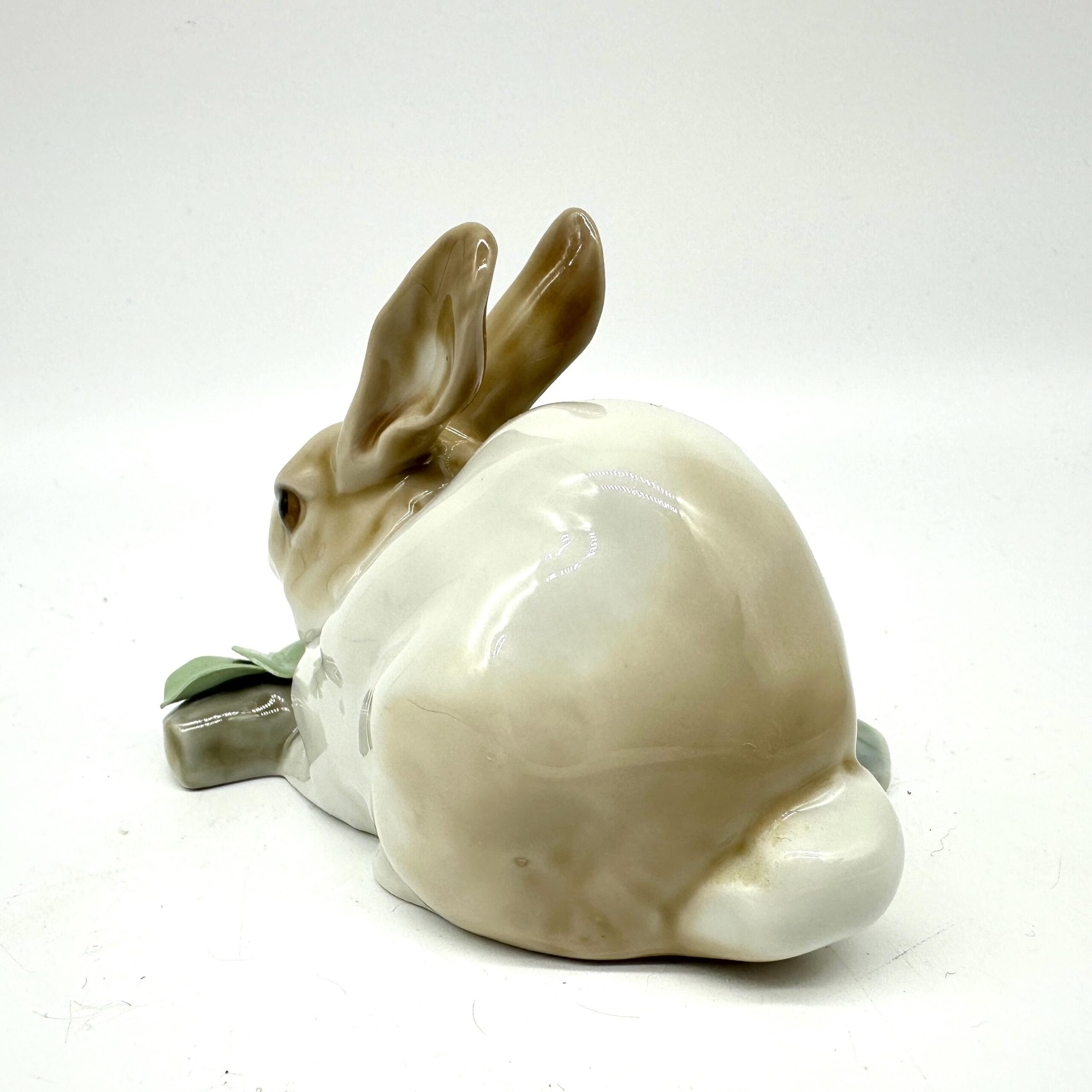 Lladro rabbit porcelain figurine captured from rear-left position showing rounded body, attentive ear posture, and green bota