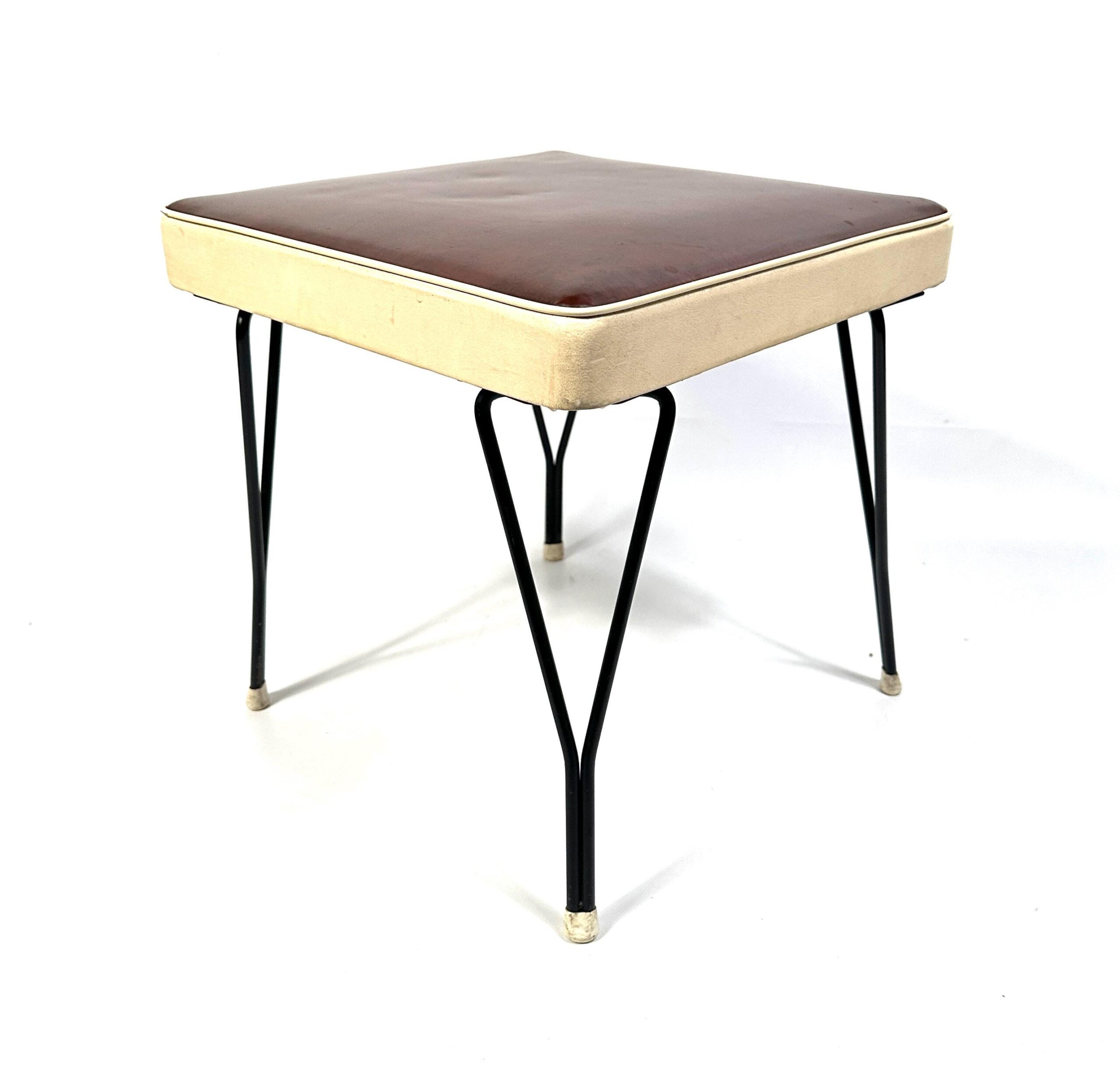 Mid-century Scandinavian stool with brown vinyl seat, cream trim, and slender black metal hairpin legs, angled three-quarter 