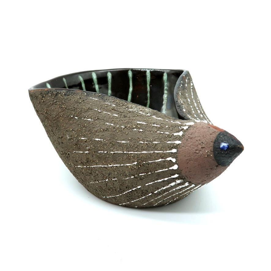 Nittsjö stoneware hedgehog bowl by THO, three-quarter view showing textured taupe exterior, white dash details, mauve face wi