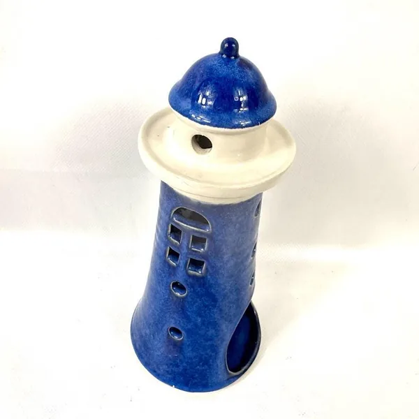 Opposite angle view of blue lighthouse candle holder, emphasizing symmetrical design and cream gallery band