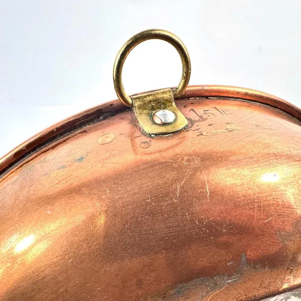 Overhead detail of solid brass hanging hardware and curved rim edge of vintage copper wall plate