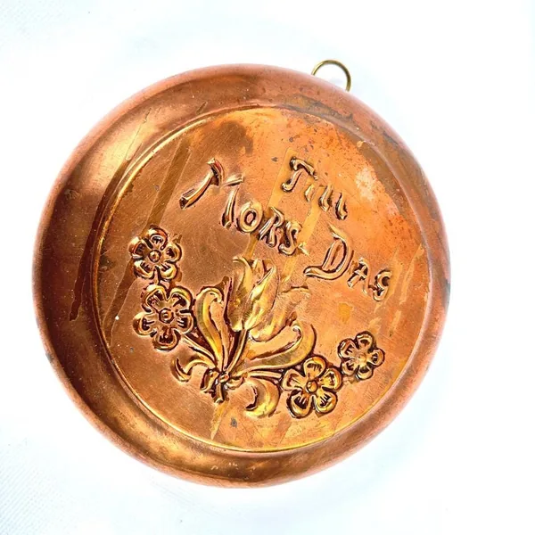 Overhead perspective of copper wall plate displaying 'Til Mor-Dag' inscription with stylized floral wreath pattern