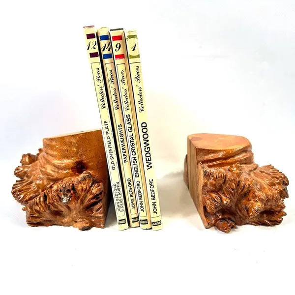 Pair of carved burl wood bookends with vintage books stacked between them, displaying rich honey-brown grain and natural root