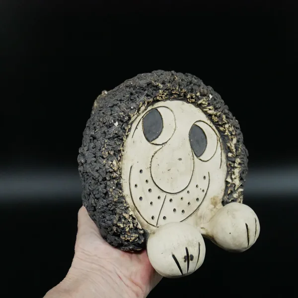 Pottery lion cradled in palm showing textured mane detail and smooth ceramic body proportions from intimate angle