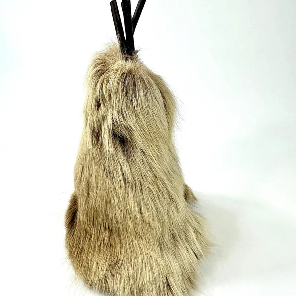 Rear view of cream-colored reindeer skin teepee showing natural fur texture, wood poles, and black binding at back opening