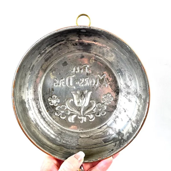 Reverse side of copper wall plate showing maker's marks and silvered patina from aging and display