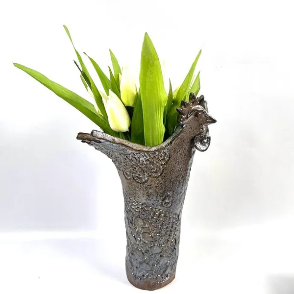 Rooster vase full presentation with fresh green plants arranged inside, textured ceramic glaze visible, and sculptural form c