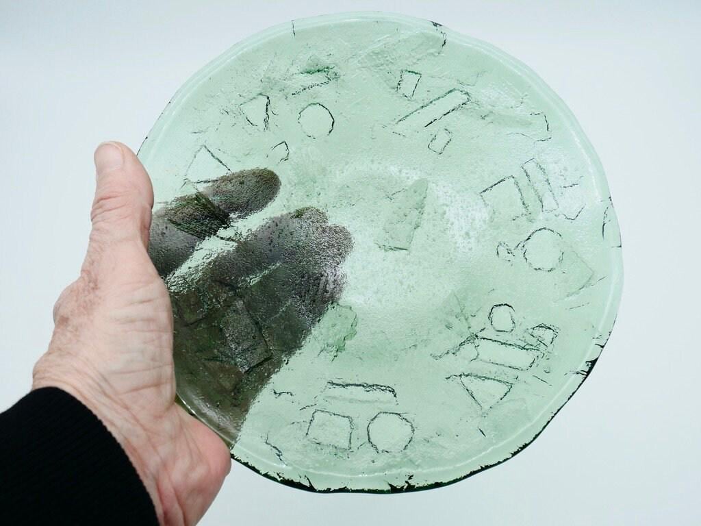Ruda green glass plate held in hand showing scale, weight, and surface finish detail