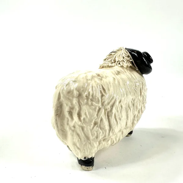 Scottish pottery ram viewed from back left angle, textured cream body fills frame, black horns curved upward