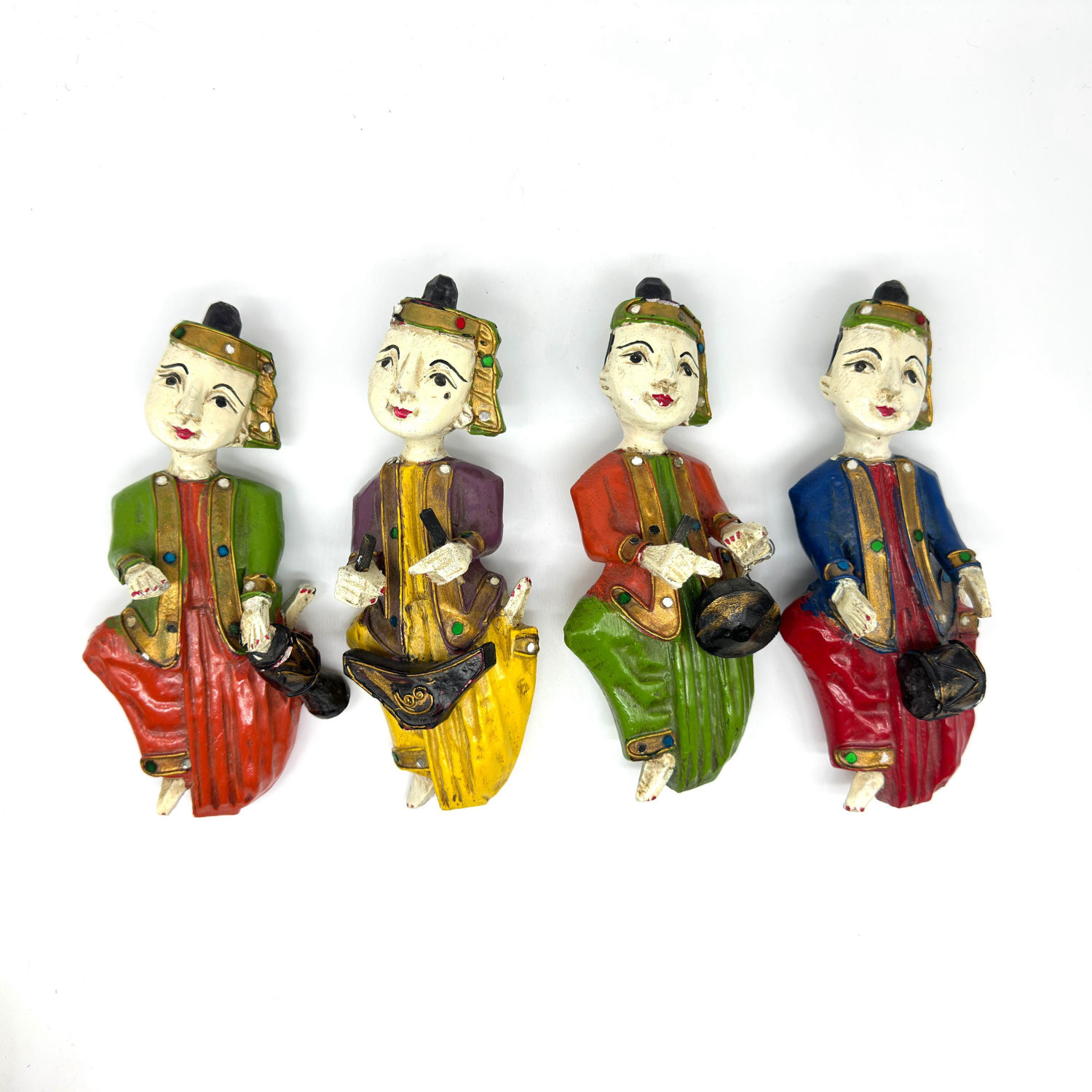 Set of four hand-carved Burmese musician wall sculptures in vibrant green, red, yellow, and blue painted wood with traditiona