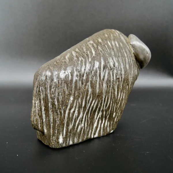 Side-lying angle of ceramic bison showing complete form and natural patina of vintage Scandinavian studio pottery