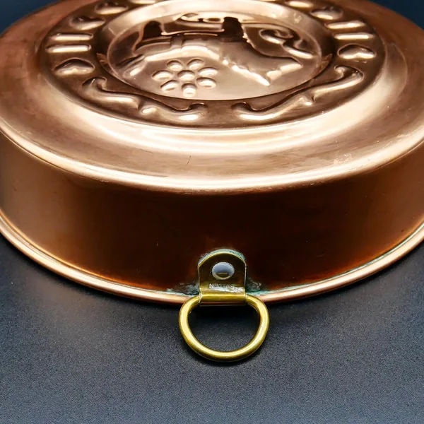 Side profile of copper mold showing smooth rounded edge and brass ring suspension