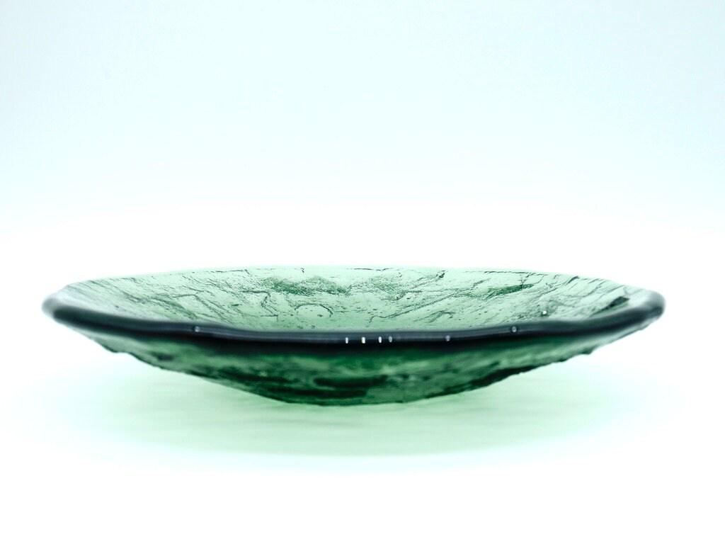 Side profile of vintage Ruda green glass plate showing curved depth and textured surface detail