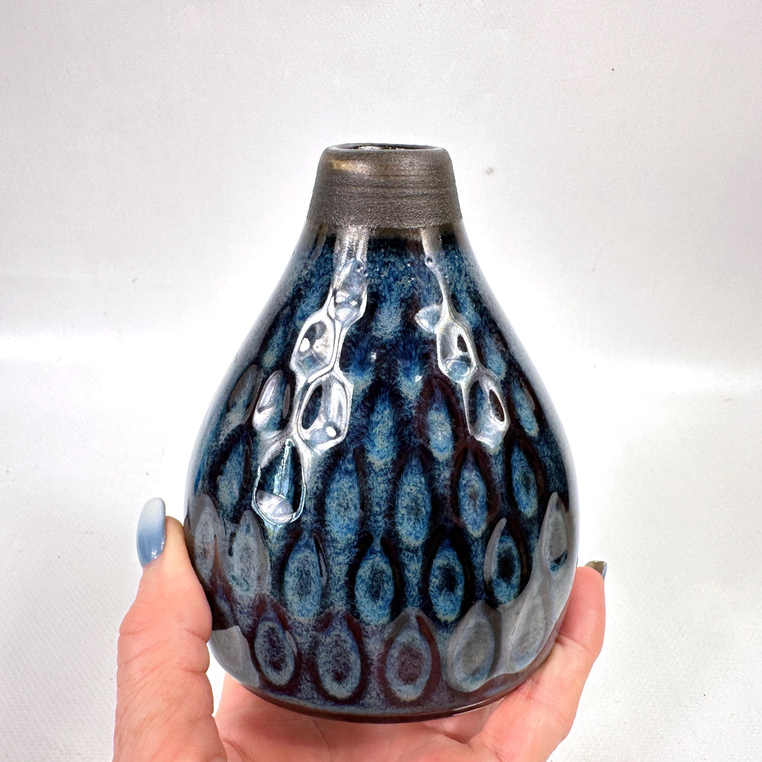 Søholm Stentøj model 3328 vase in deep blue stoneware with white relief leaf pattern, held in hand showing teardrop form