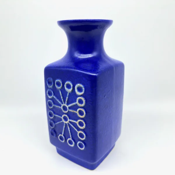 Sputnik vase side angle showing cube base, circular relief motif, and tapered neck form