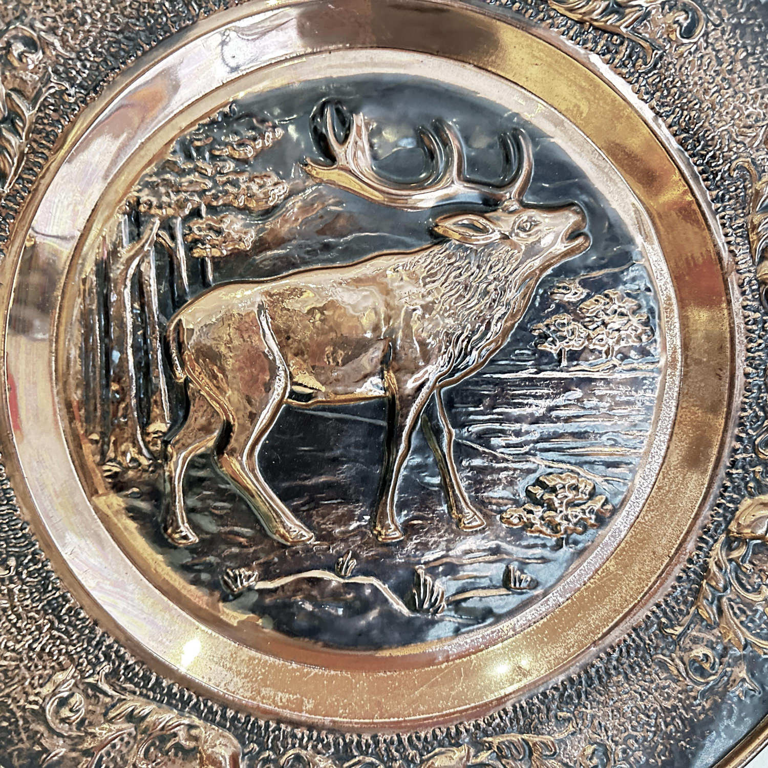 Stag profile view on copper plate showing detailed antlers and standing pose against woodland background