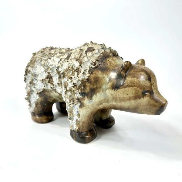 Stoneware bear positioned to show left-side profile with textured surface and bronze glaze beneath cream-colored aging