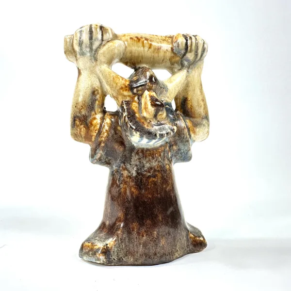 Straight-on portrait view of ceramic Viking figure with hollow eye sockets, textured facial features, golden arm glaze