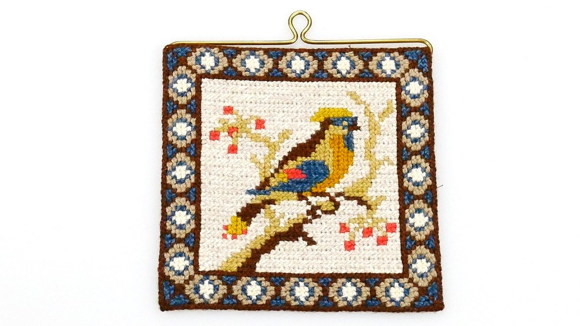 Swedish 1970s hand-embroidered wool tapestry featuring a colorful bird perched on branch with scattered berries, geometric pa