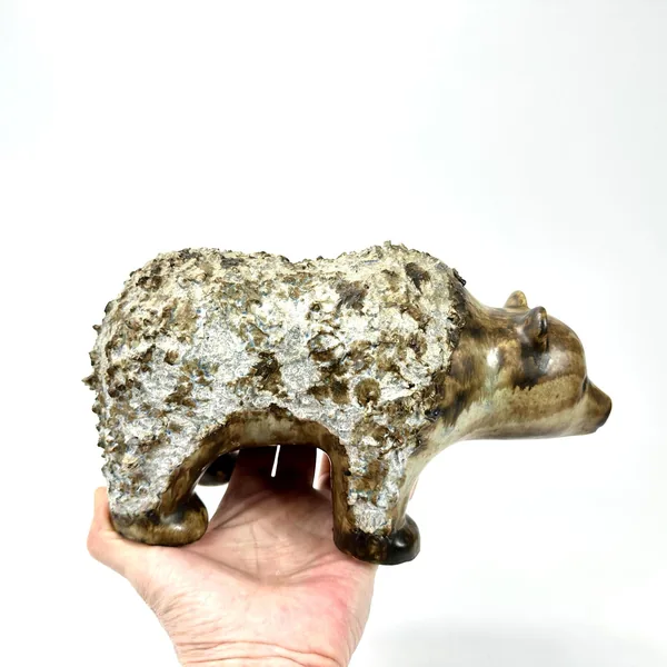 Swedish EGO Stengods ceramic bear, hand-held view showing textured stoneware with whitened patina and warm bronze underglaze