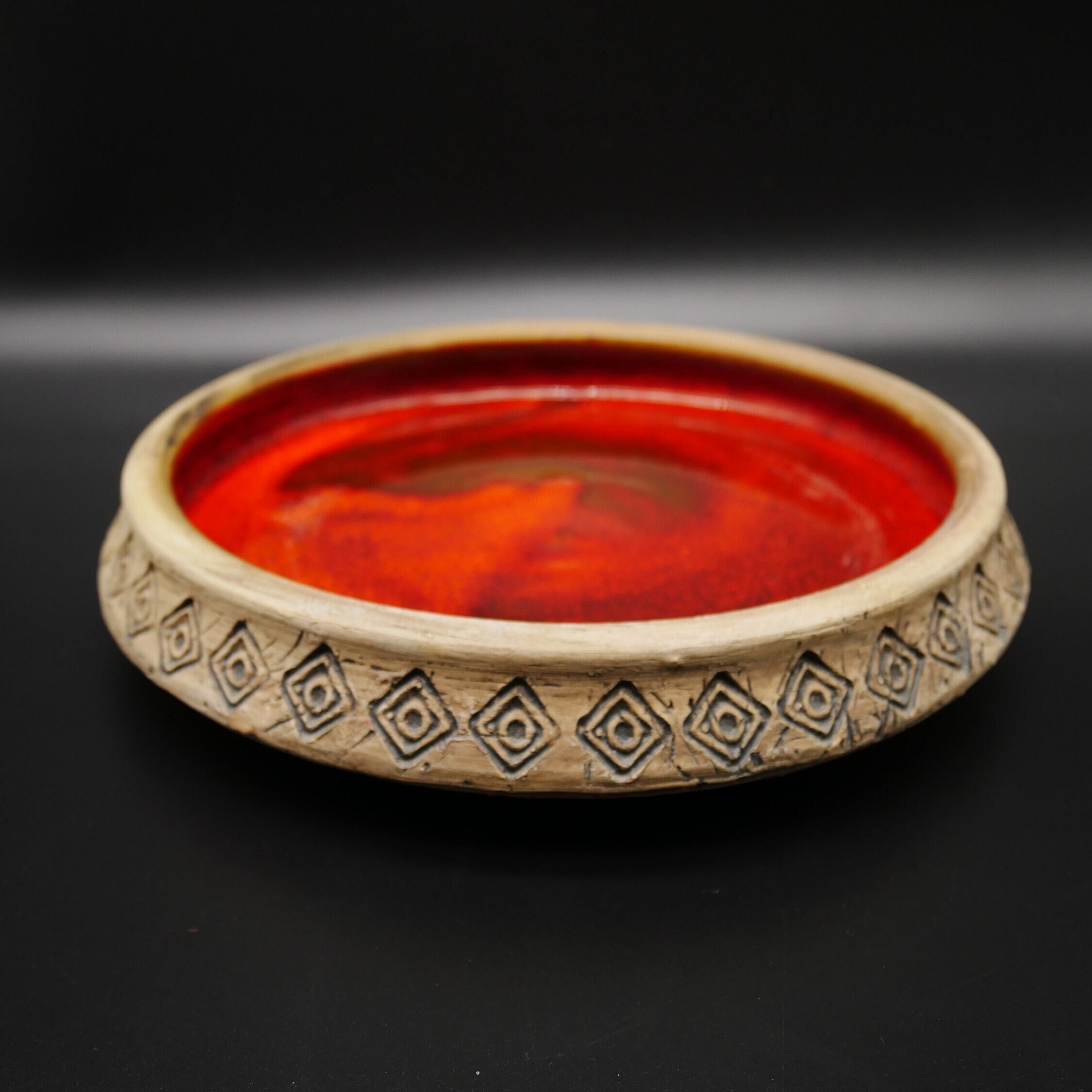 Swedish Fat Lava ceramic bowl, 1960s, orange-brown glaze with carved diamond rim pattern, overhead view