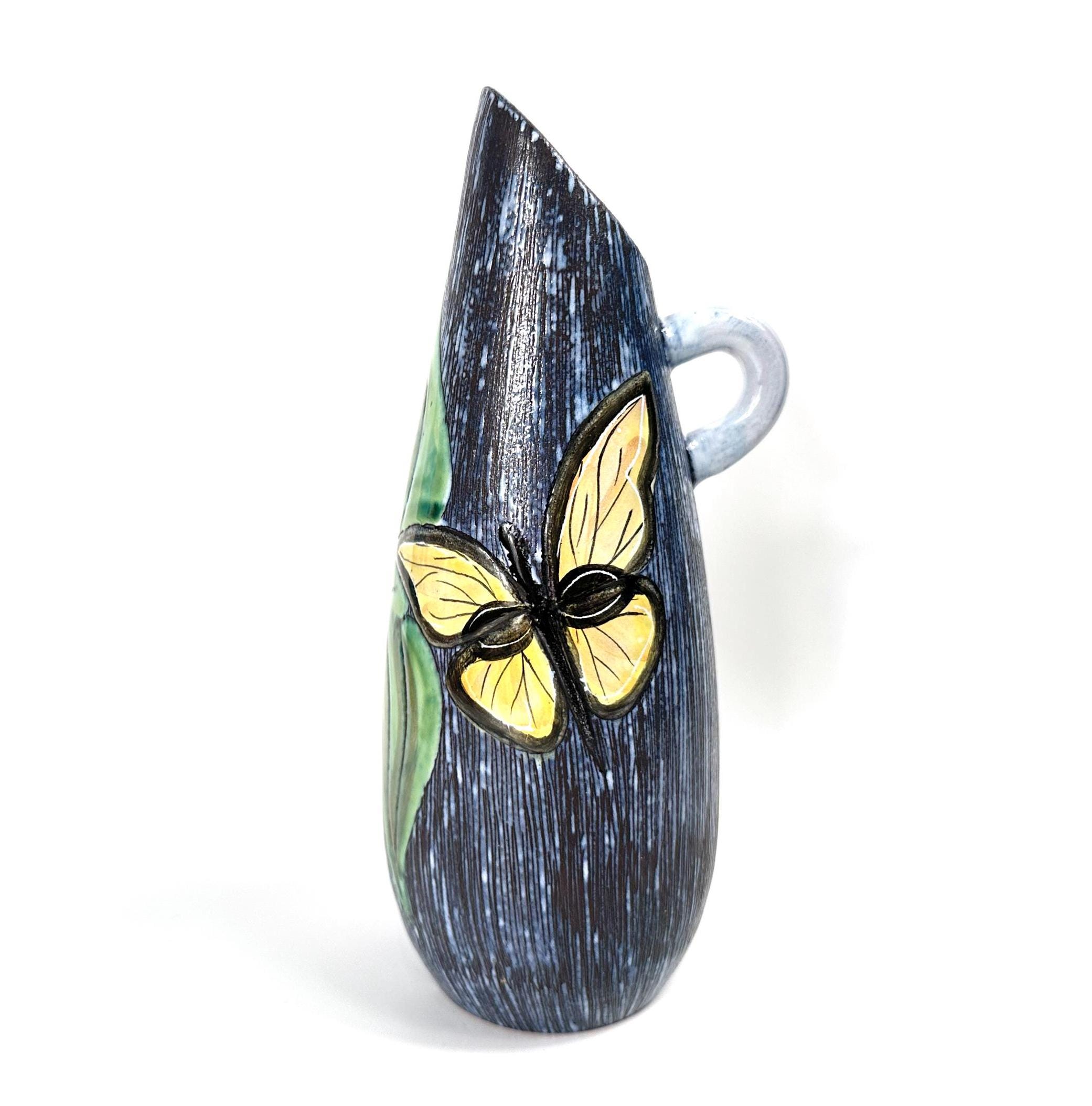 Swedish stoneware vase with sgraffito butterfly design, dark blue textured body, yellow hand-painted butterfly, and clear gla