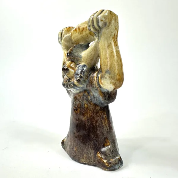Three-quarter angle view of ceramic figure showing side profile, single raised arm silhouette, dark aged base foundation