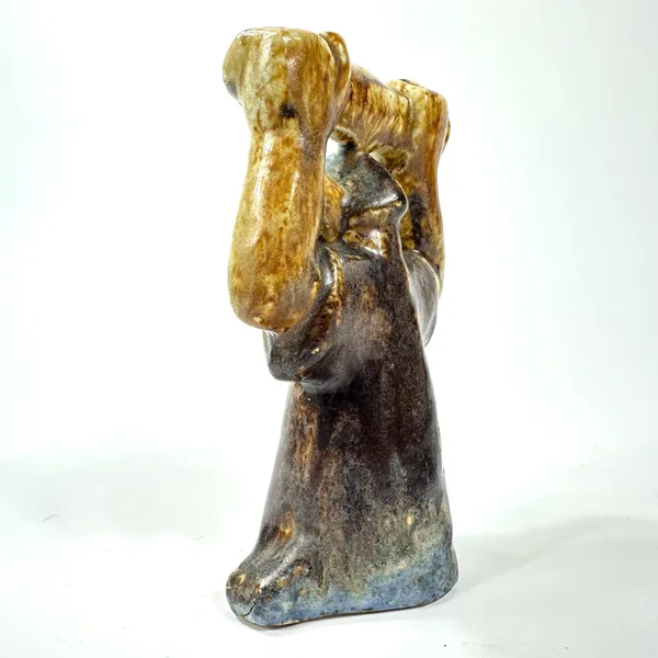 Tilted angle view of ceramic Viking sculpture showing upper body glaze work, arm positioning, conical base structure