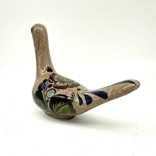 Tonalá bird pottery from side angle, showing detailed hand-painted leaf and berry motifs in blue and green on cream ceramic b