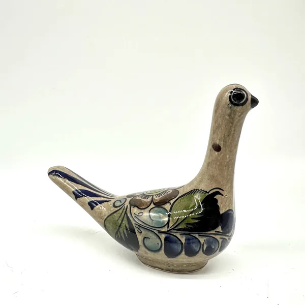 Tonalá bird pottery photographed from right side, showing distinct blue berry clusters and green leaf motifs on cream base