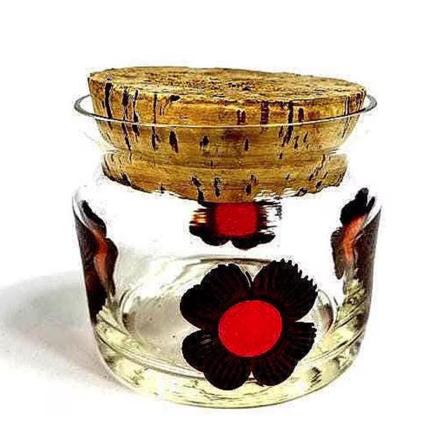 Vintage 1970s glass storage jar with hand-painted brown flowers and orange centers, cork basket weave lid, full front view