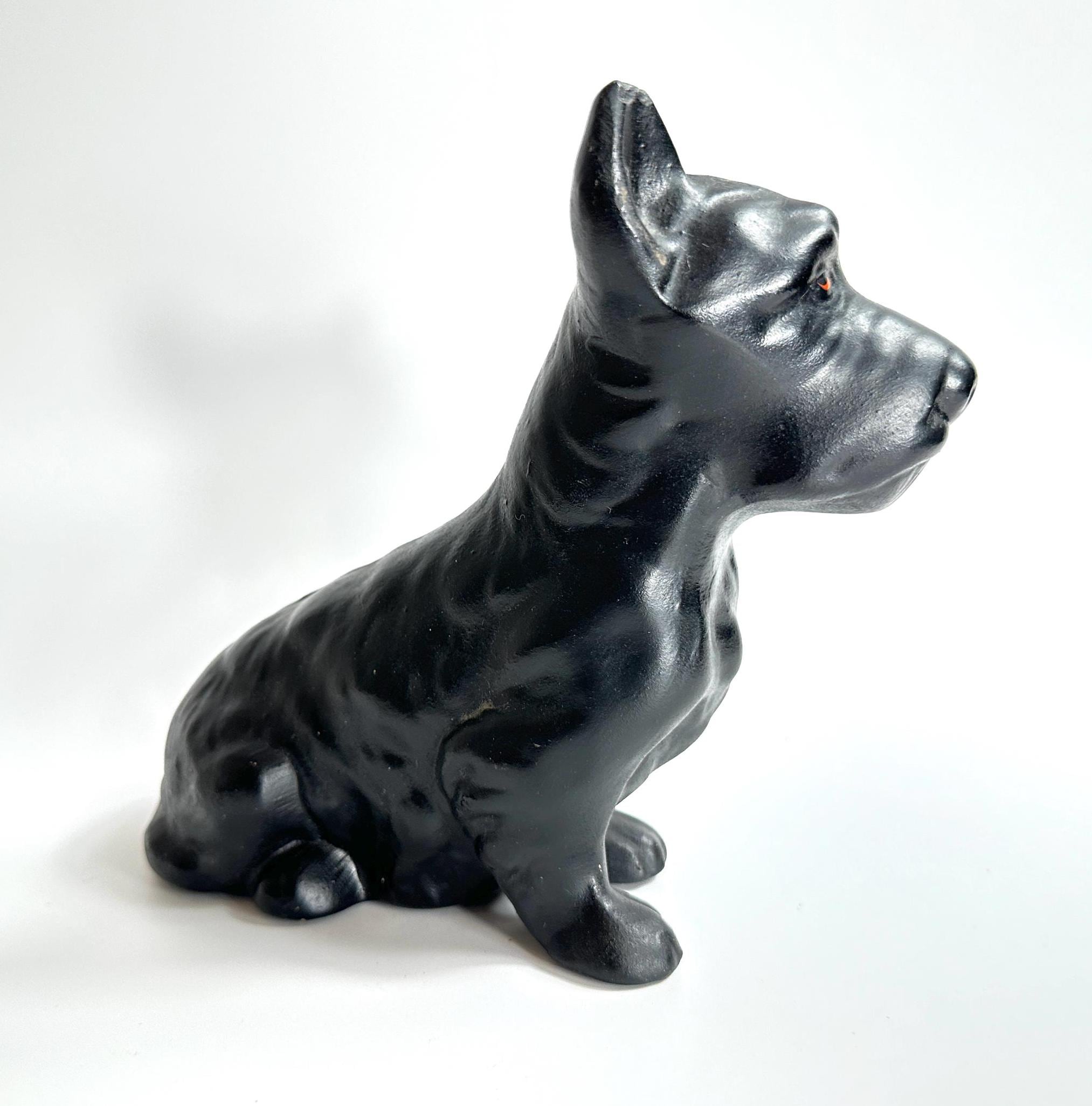 Vintage black ceramic Scottish Terrier figurine, glossy finish, seated profile view showing alert posture and distinctive bre