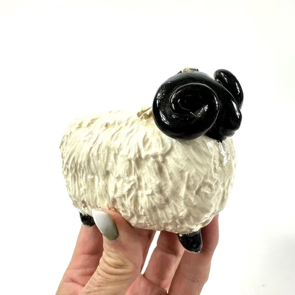 Vintage ceramic sheep held in hand, scale reference showing compact size, cream textured body with black features