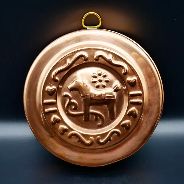 Vintage copper cookie mold with Swedish Dala Horse relief, brass hanging ring, dark background