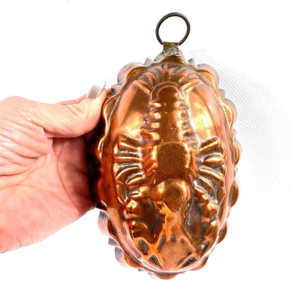 Vintage copper mold held in hand showing scale, weight, and amber copper finish