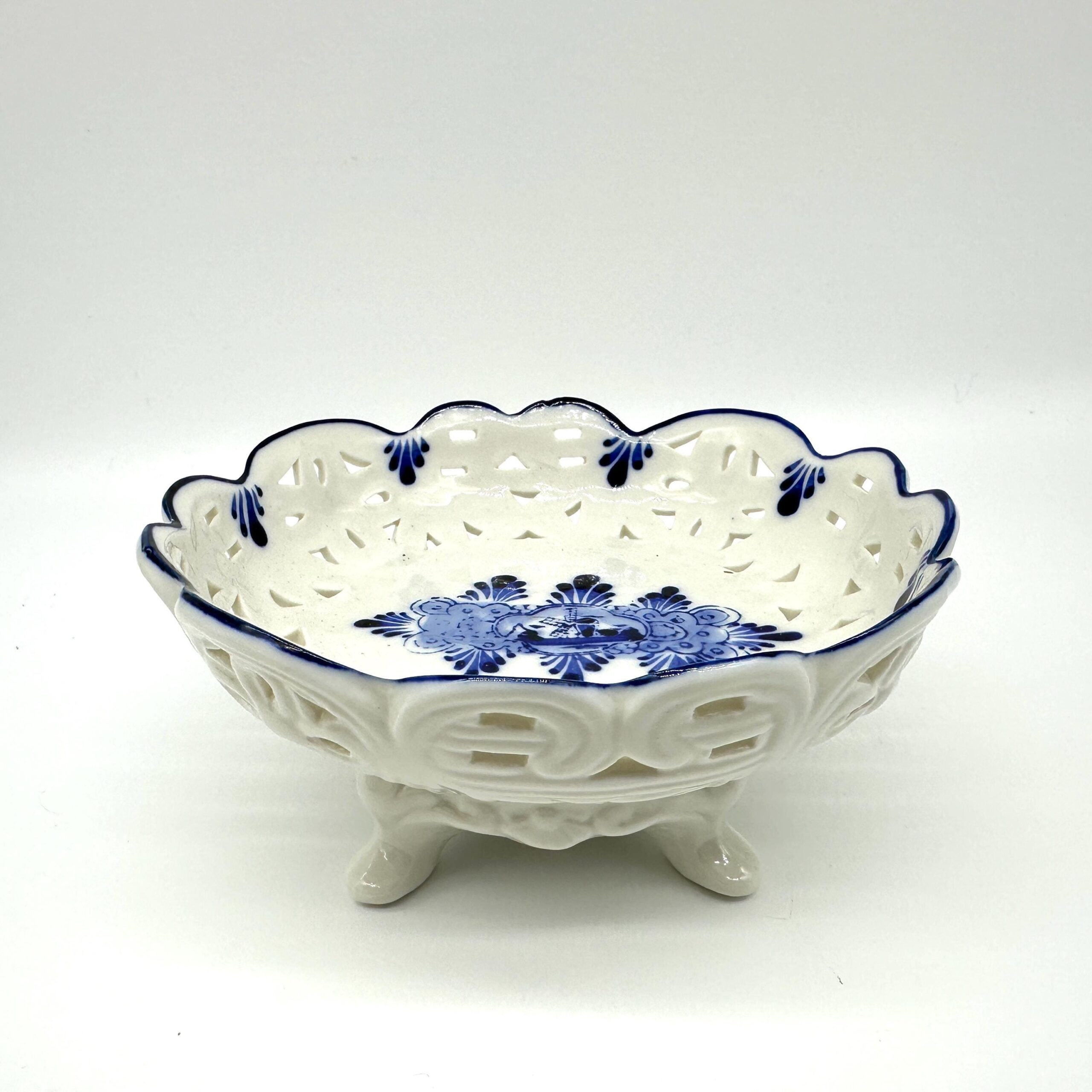 Vintage Delft-style porcelain footed bowl with pierced lattice sides, cream glaze, cobalt blue windmill motif, scalloped rim