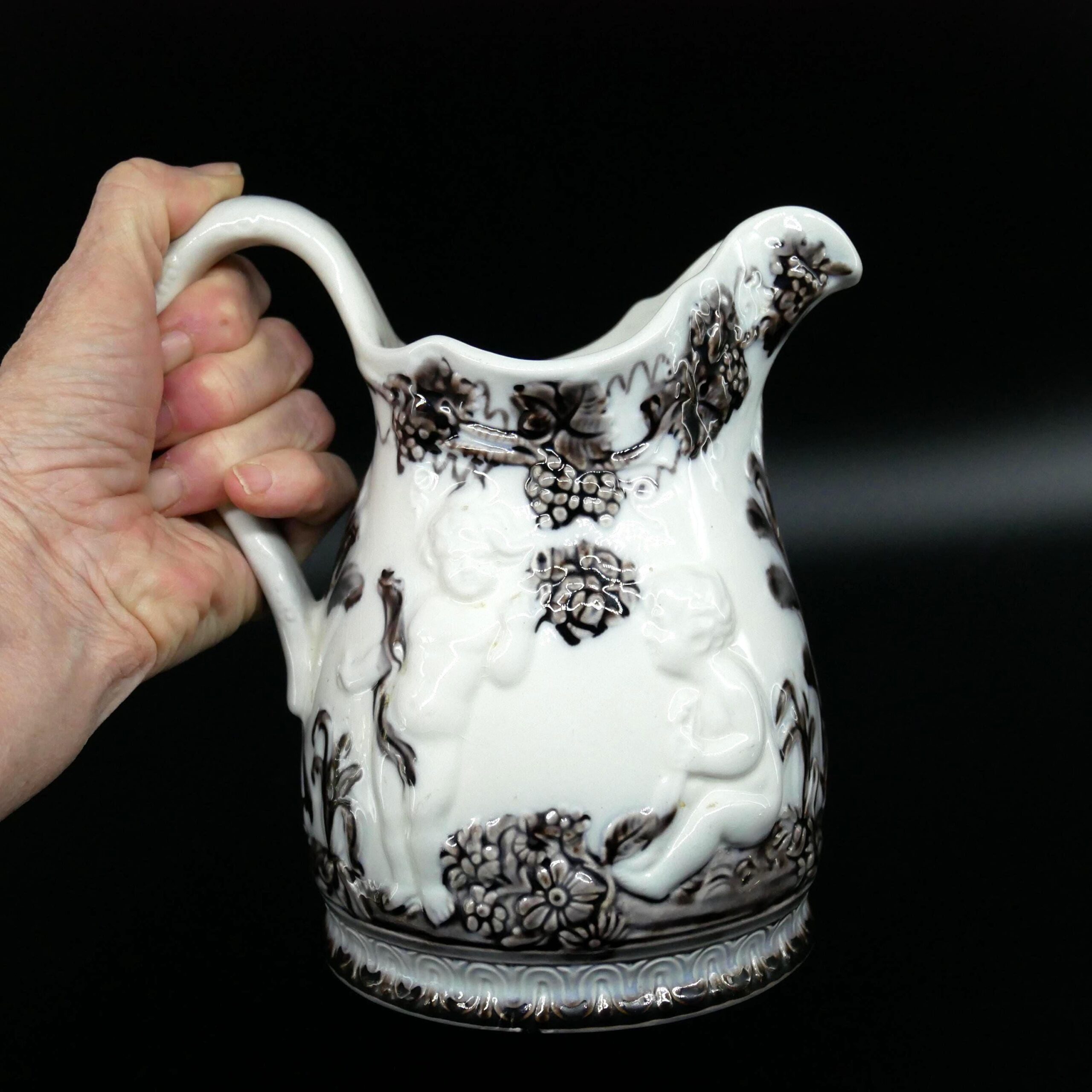 Vintage Gefle ceramic pitcher with brown cherub design, cream glaze, held in hand showing scale and elegant curved handle