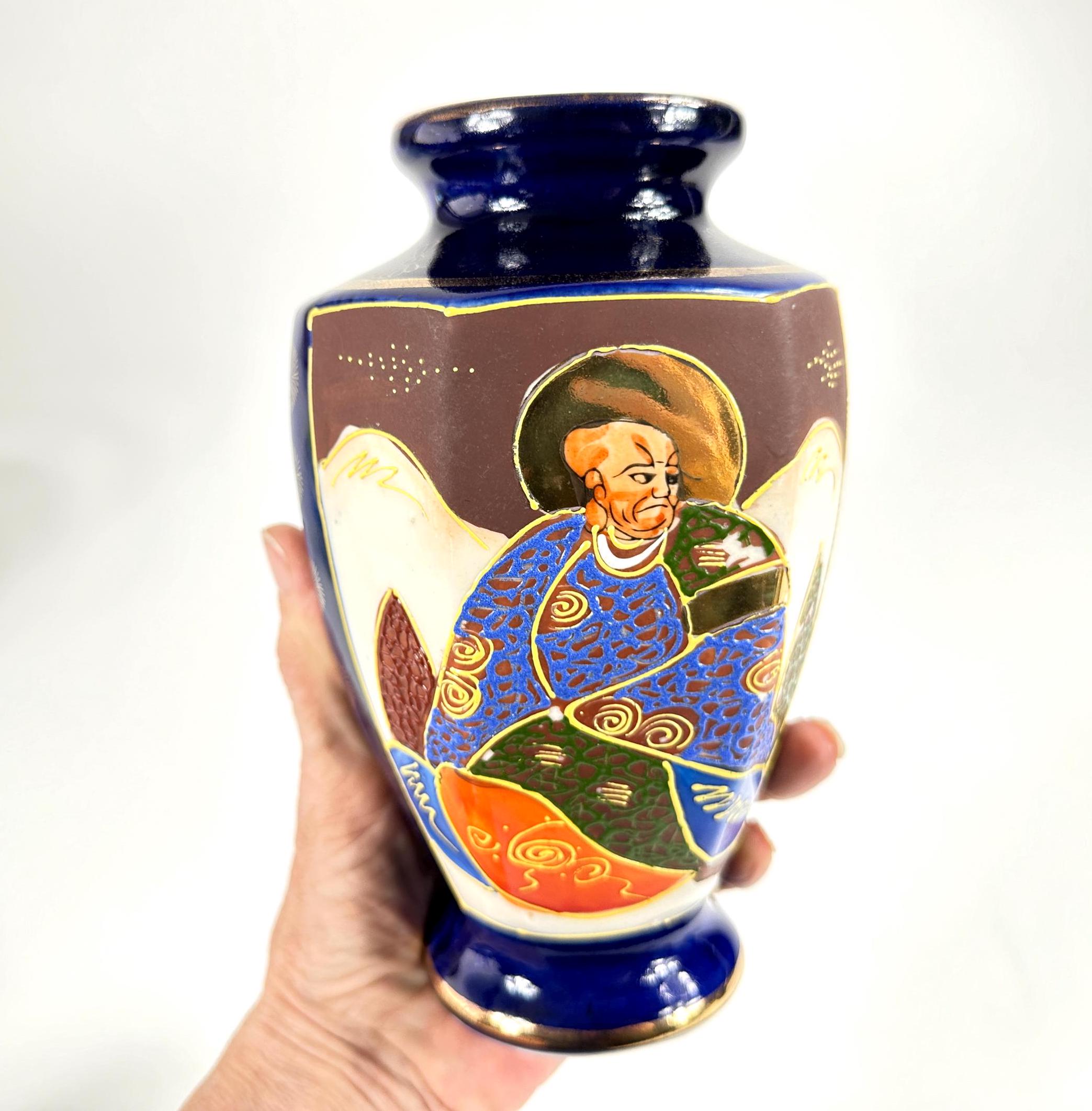 Vintage Japanese Satsuma porcelain vase with hand-painted figure in blue robe and raised gold moriage details, held in hand