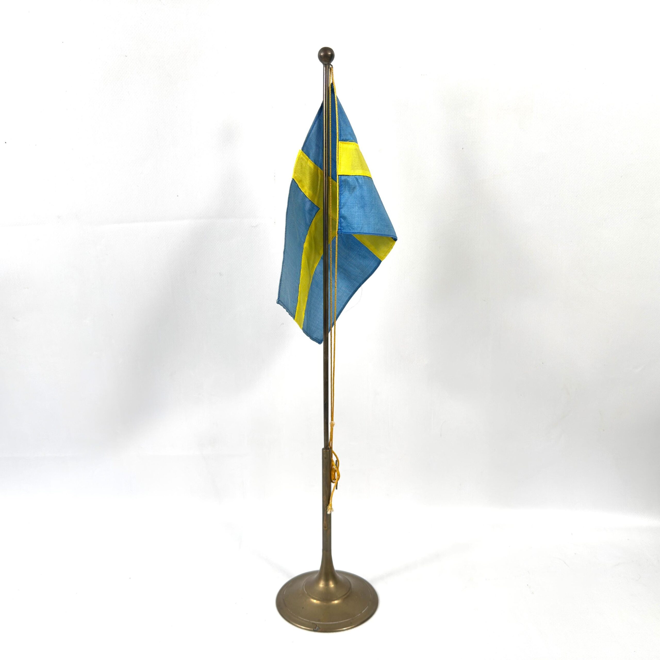 Vintage Swedish table flag with blue and yellow fabric on brass stand, full view against neutral background