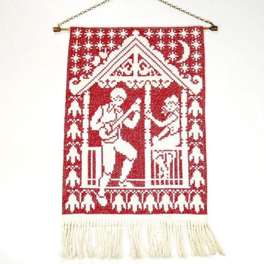 Vintage Swedish wool tapestry wall hanging with red cross-stitch serenade scene, cream fringe, brass hanger