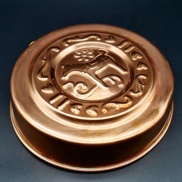 Warm-toned copper mold with Dala Horse relief, viewed from below at slight angle