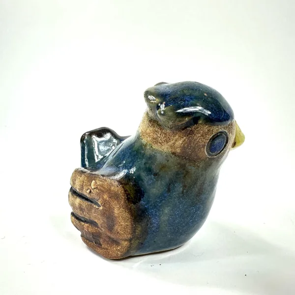 Willy Fischer bird ceramic shown from left-facing angle, yellow beak prominent and wing feather texture clearly visible