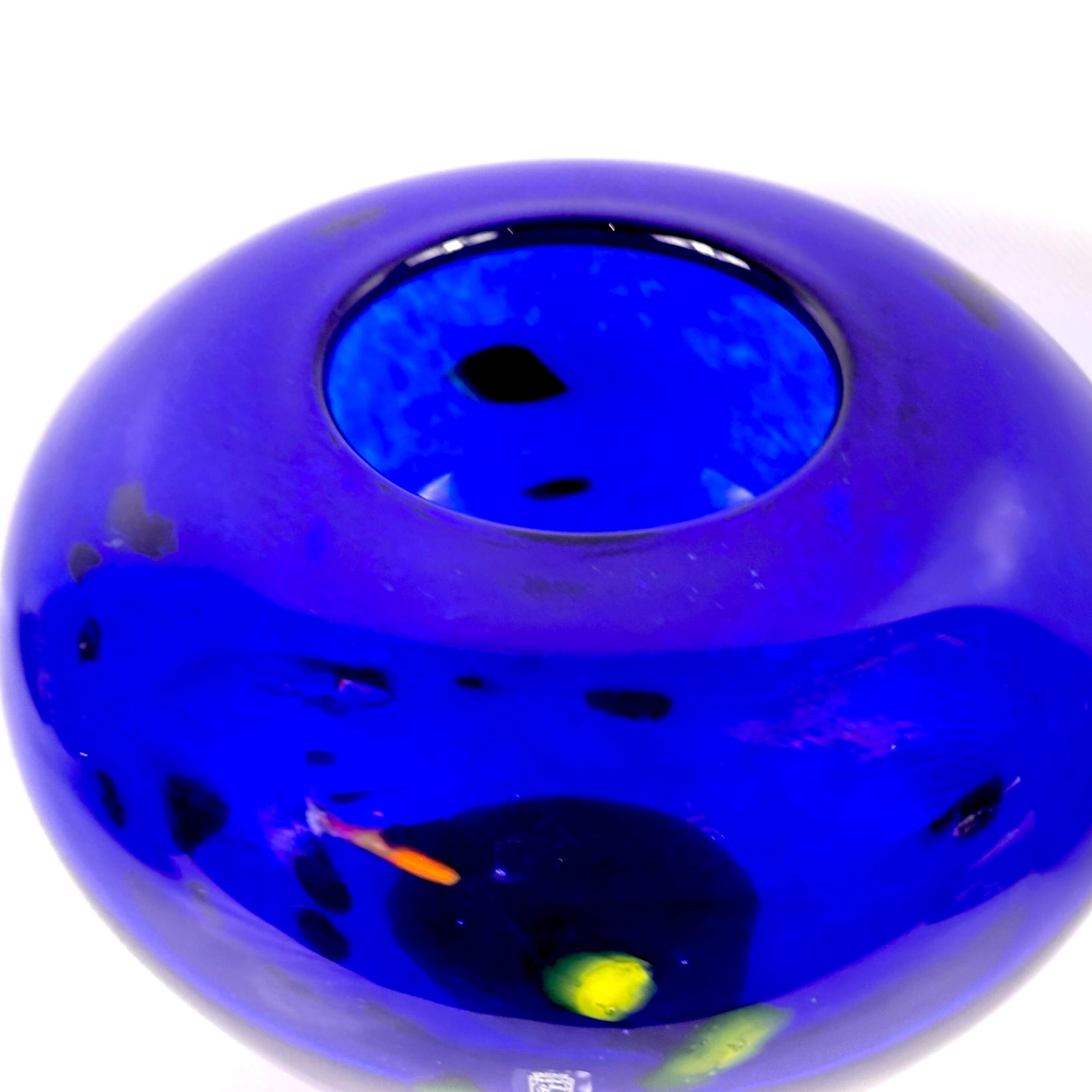 Angled side view emphasizing the organic color inclusions and bowl profile of the blue glass vessel
