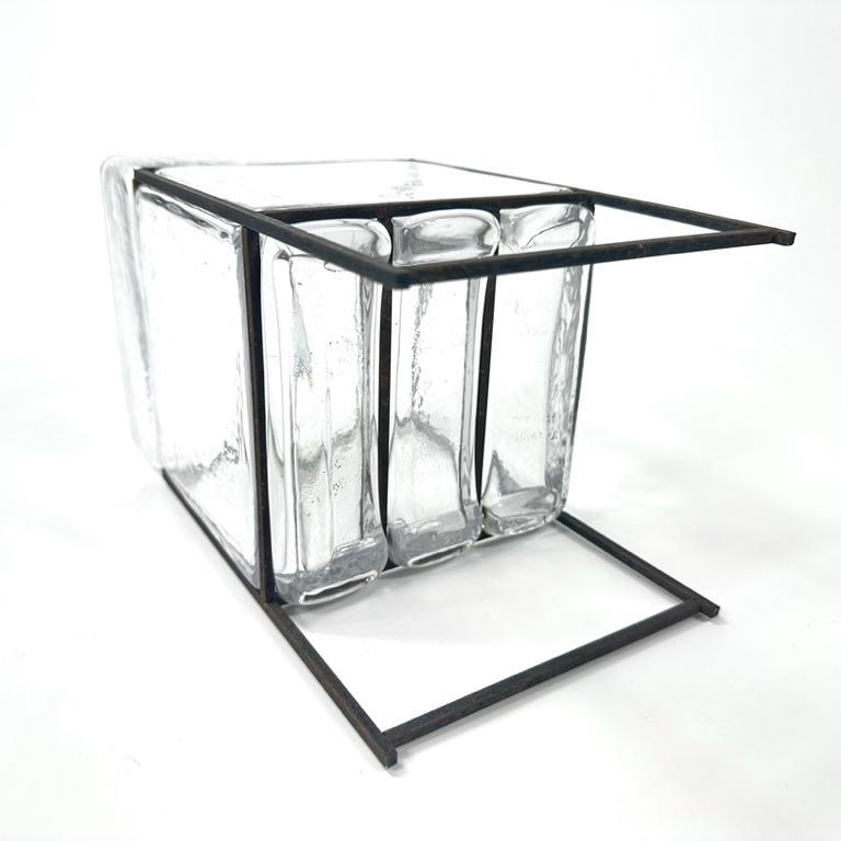 Angled three-quarter overhead view showing glass cube structure, black iron framework edges, and open interior depth