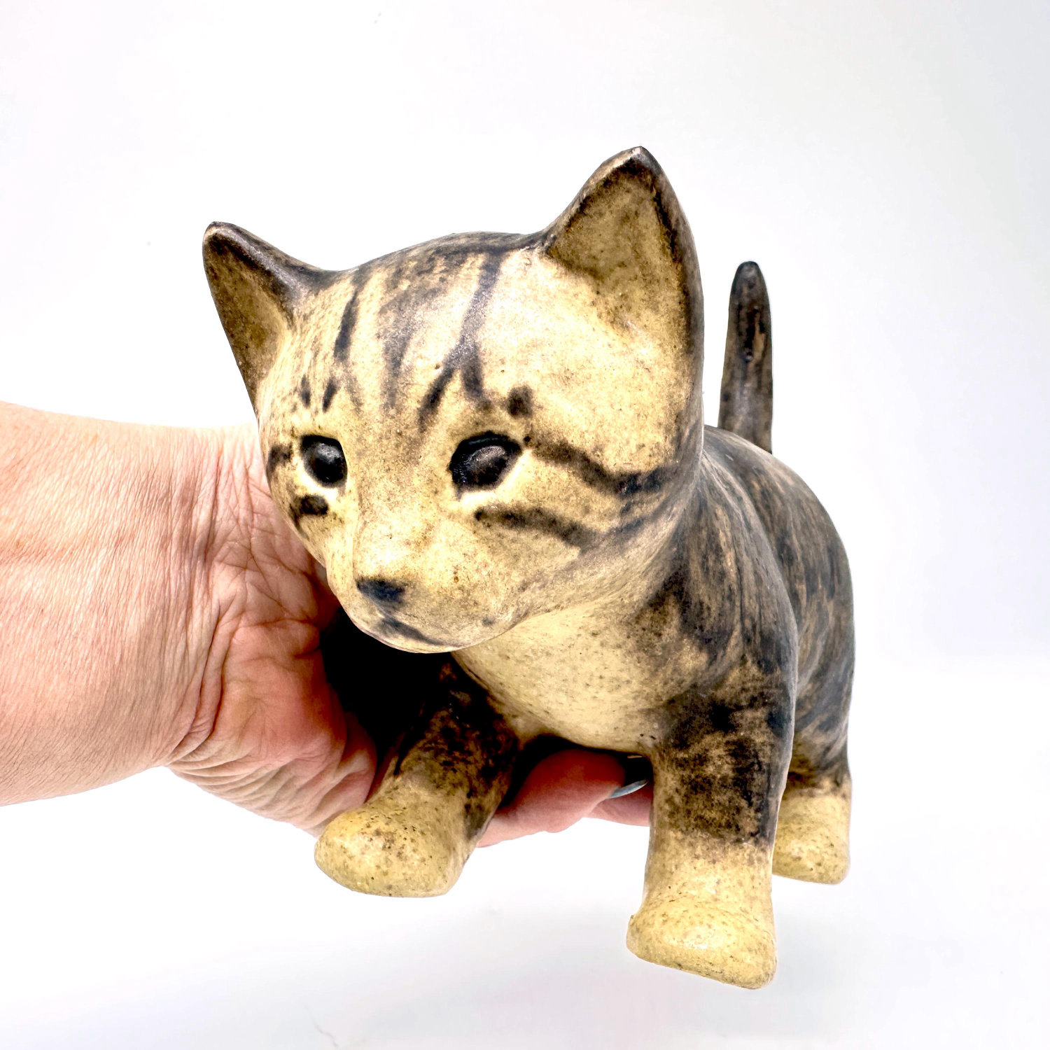 Ceramic cat figurine held in hand showing scale, tactile glaze surface texture, and vintage patina character