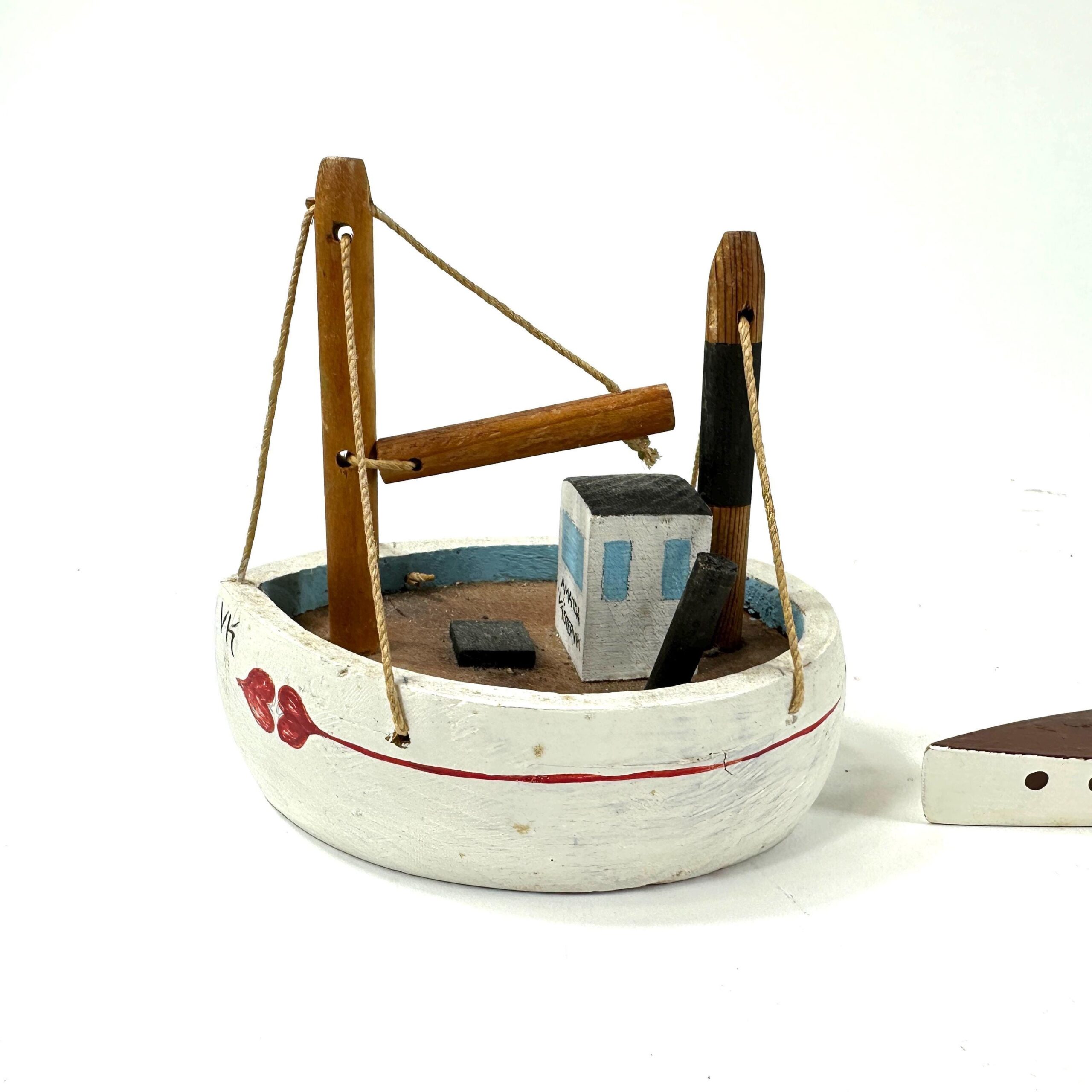Close-up of white wooden boat hull with handcrafted mast rigging and folk art cabin paintwork in detail