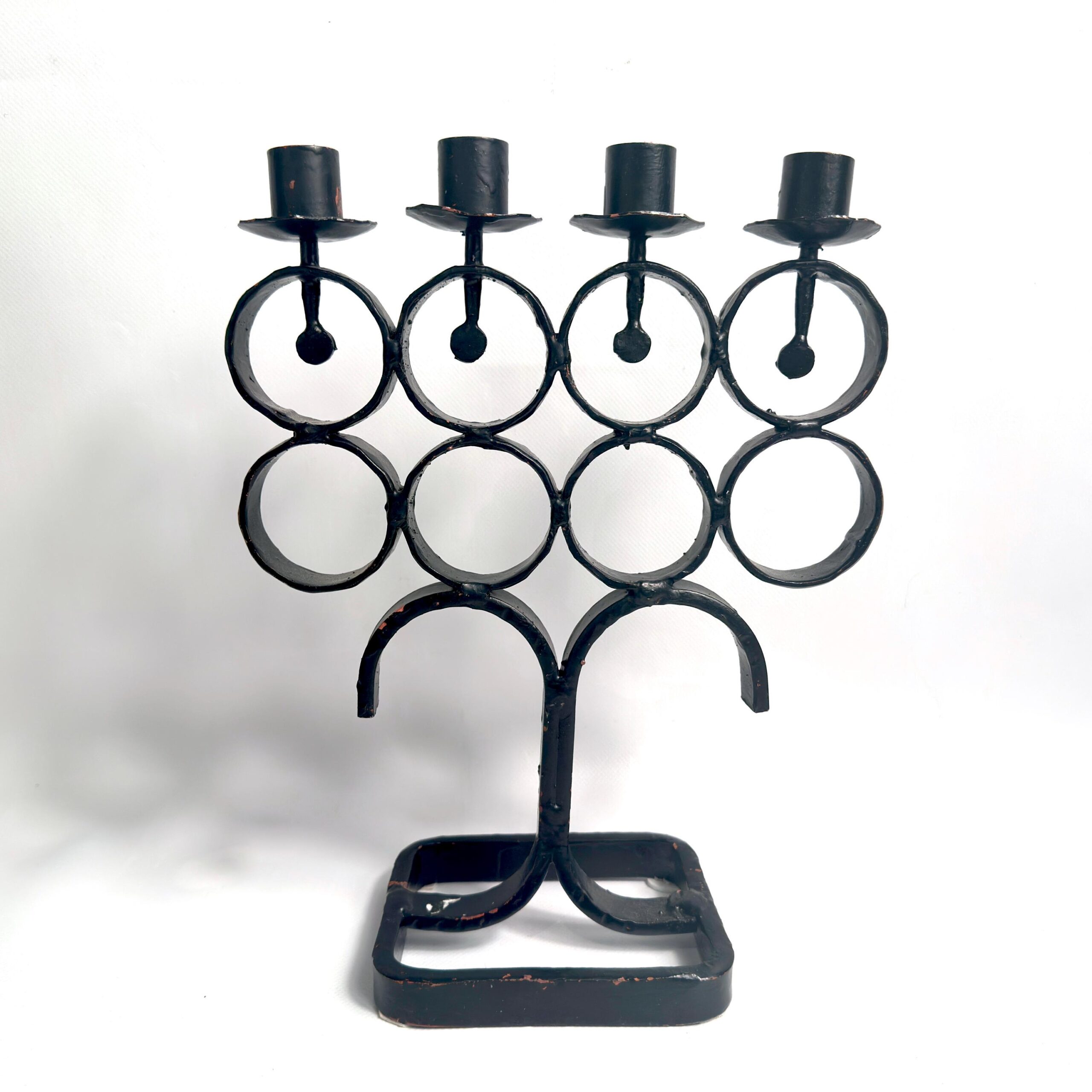 Direct front view of iron candelabra without candles, showcasing four empty cup holders and layered ring structure