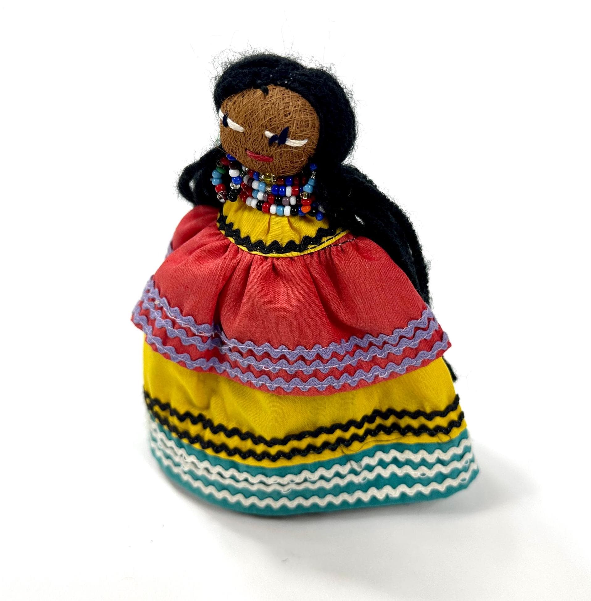Doll positioned at slight angle displaying black hair drape, yellow-trimmed beaded collar, and full geometric patterned texti