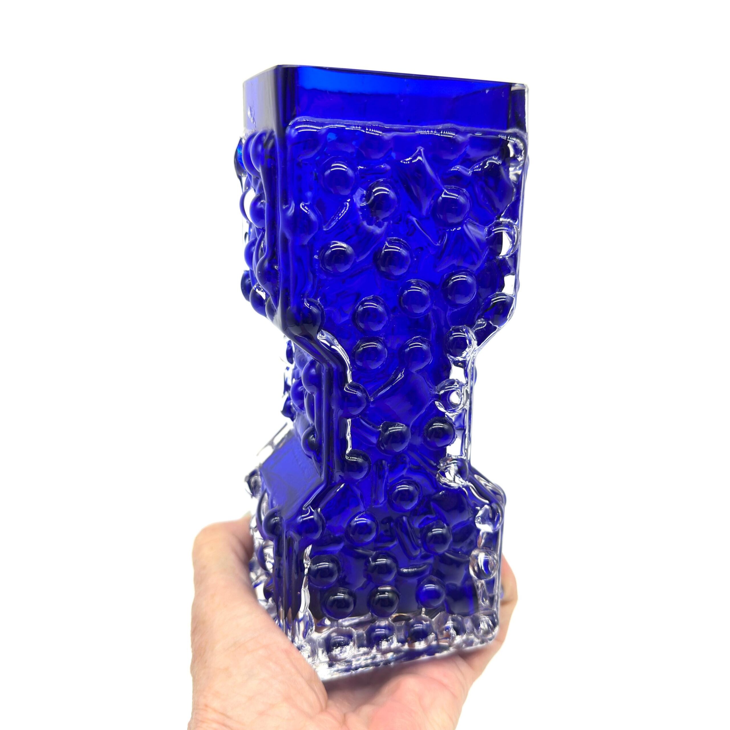 Handheld vase slight angle view showing full hourglass silhouette clear base transparency bubble-textured cobalt body detail