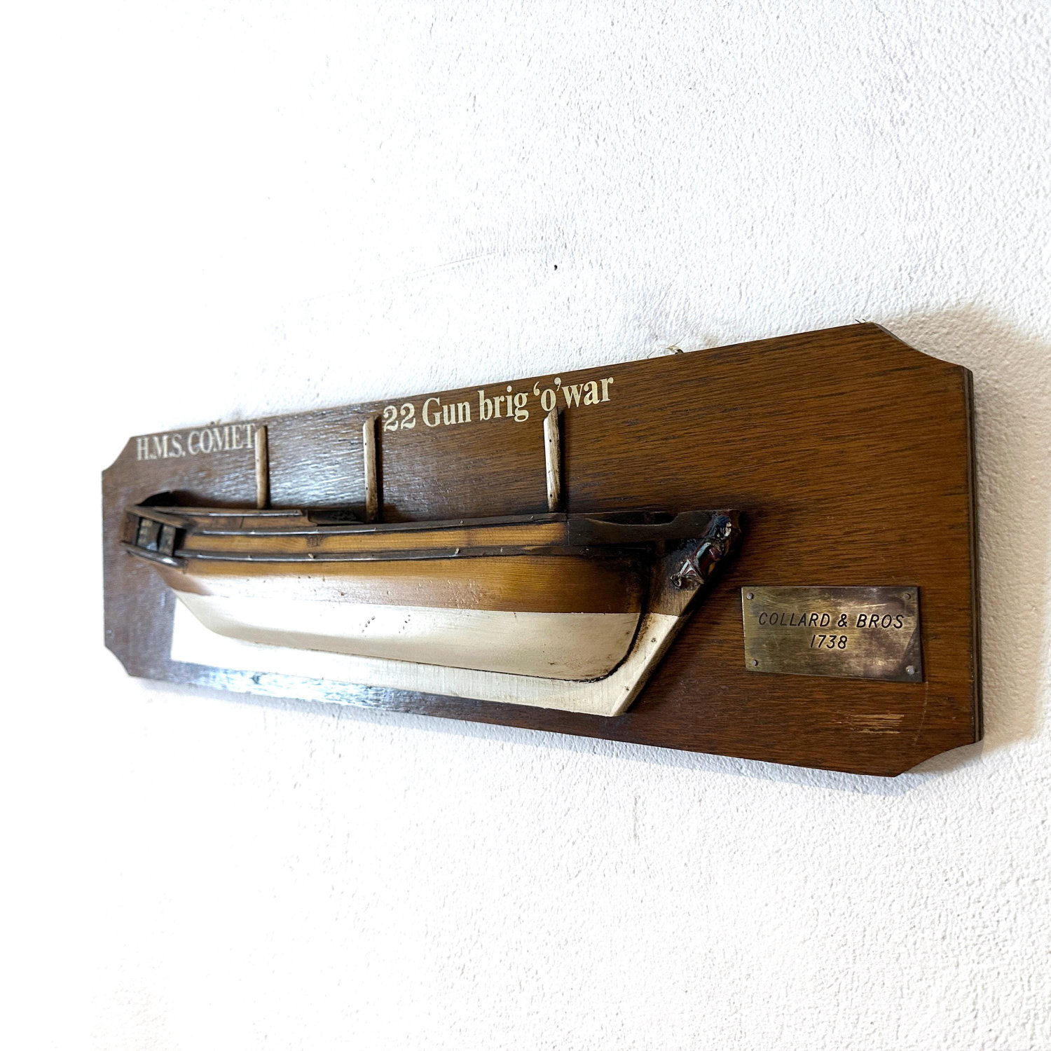 HMS Comet half hull ship model mounted on wooden plaque, angled side view showing carved hull detail and brass fittings again